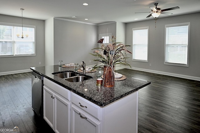 kitchen featuring dishwasher, sink, an island with sink, dark stone counters, and white cabinets