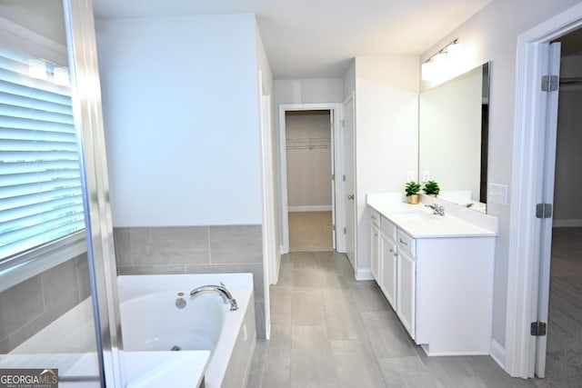 bathroom featuring a washtub, vanity, and a healthy amount of sunlight