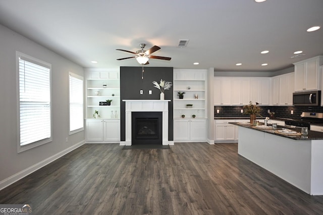 kitchen featuring appliances with stainless steel finishes, ceiling fan, dark stone countertops, dark hardwood / wood-style floors, and white cabinetry