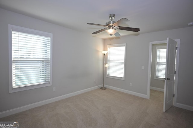 empty room featuring ceiling fan and light colored carpet