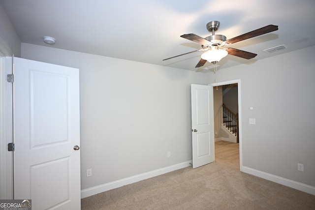 spare room featuring light colored carpet and ceiling fan