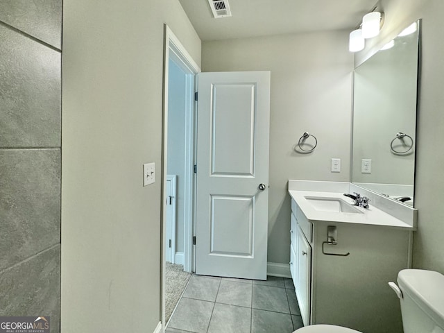 bathroom with toilet, vanity, and tile patterned floors