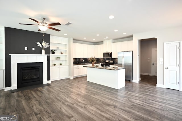 kitchen featuring a center island with sink, ceiling fan, dark hardwood / wood-style floors, appliances with stainless steel finishes, and white cabinetry