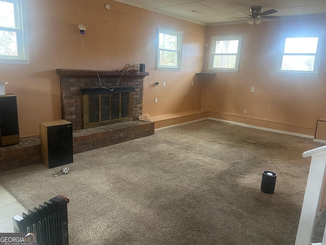 unfurnished living room featuring ceiling fan, carpet flooring, and a brick fireplace