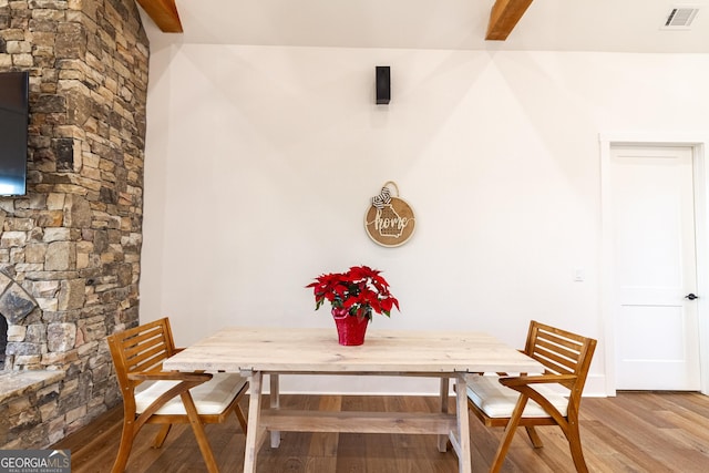 dining room featuring beamed ceiling and light hardwood / wood-style flooring