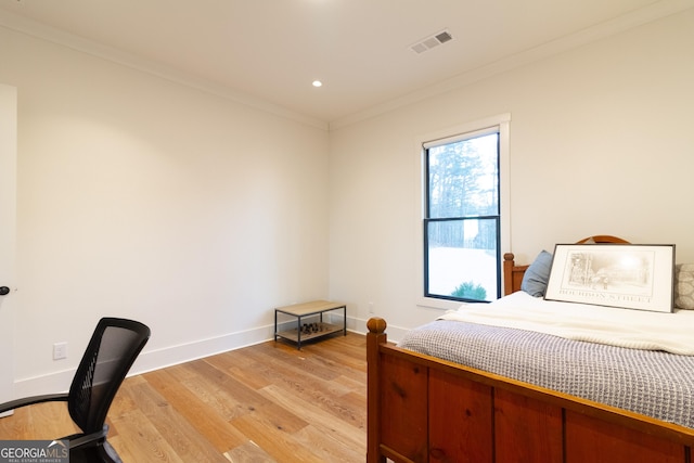 bedroom with ornamental molding and light wood-type flooring