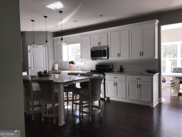 kitchen featuring pendant lighting, dark hardwood / wood-style floors, electric range, a breakfast bar area, and white cabinets