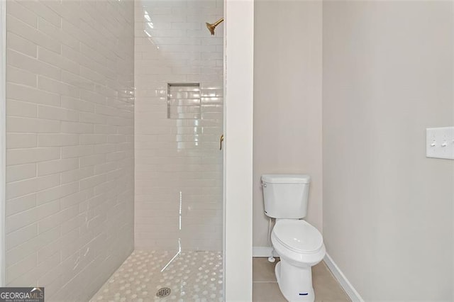 bathroom with a tile shower, tile patterned flooring, and toilet