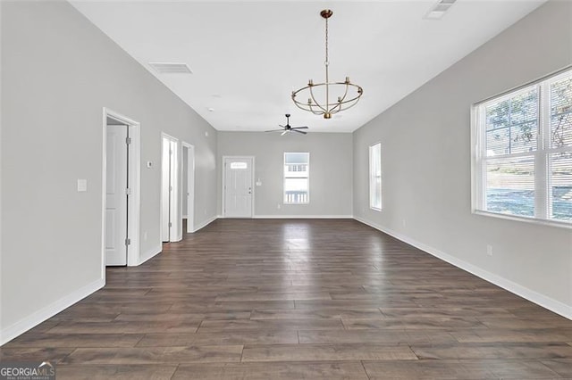 unfurnished room with dark wood-type flooring, a healthy amount of sunlight, and ceiling fan with notable chandelier