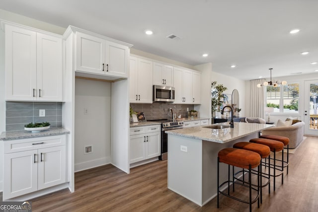 kitchen featuring white cabinets, appliances with stainless steel finishes, a center island with sink, and sink