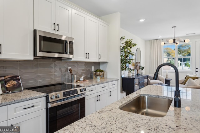 kitchen featuring white cabinets, hanging light fixtures, sink, appliances with stainless steel finishes, and a notable chandelier