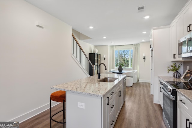 kitchen featuring white cabinetry, a kitchen island with sink, sink, and appliances with stainless steel finishes