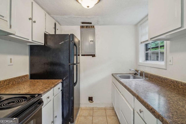 kitchen featuring white cabinets, black refrigerator, sink, light tile patterned floors, and a textured ceiling