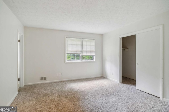 unfurnished bedroom with light carpet, a closet, and a textured ceiling