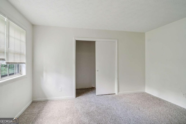 unfurnished room featuring a textured ceiling and light colored carpet