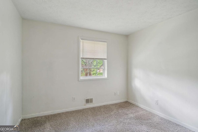 empty room with carpet and a textured ceiling