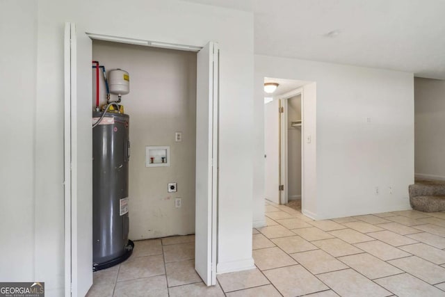 interior space with washer hookup, electric dryer hookup, light tile patterned floors, and water heater