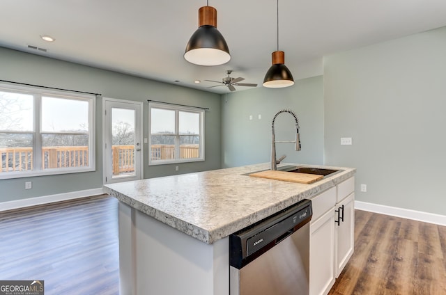 kitchen with stainless steel dishwasher, sink, a center island with sink, white cabinets, and hanging light fixtures