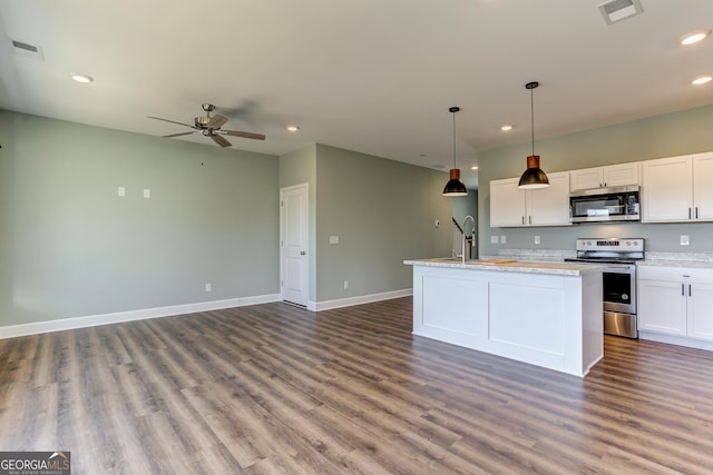 kitchen with white cabinetry, sink, stainless steel appliances, decorative light fixtures, and a center island with sink