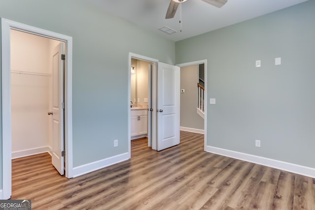 unfurnished bedroom featuring a closet, a spacious closet, ceiling fan, and light hardwood / wood-style floors