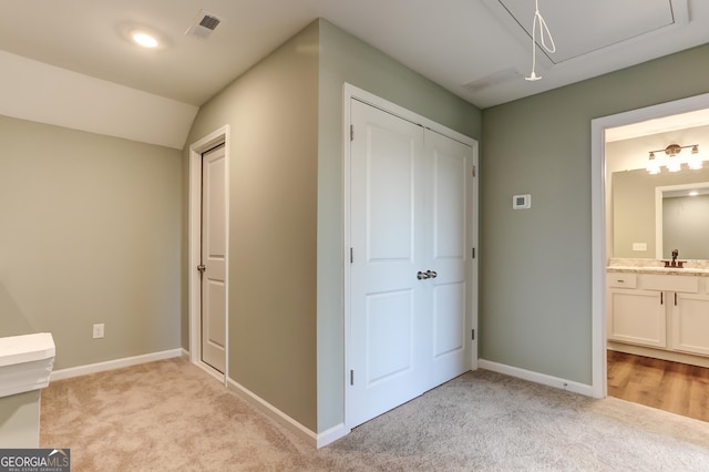 interior space with ensuite bath, light carpet, a closet, and sink