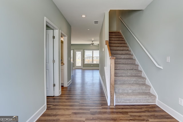 stairway with ceiling fan and wood-type flooring