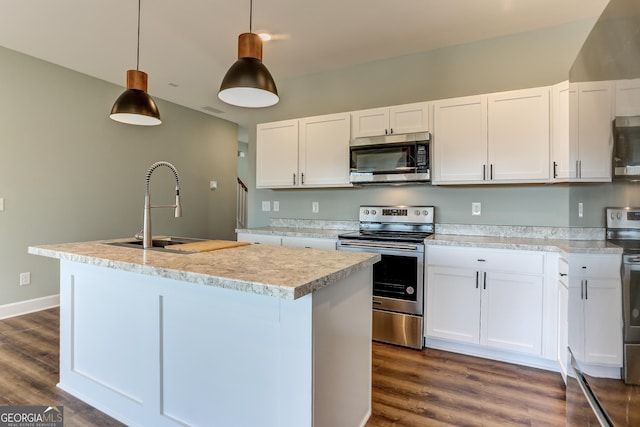 kitchen with stainless steel appliances, a kitchen island with sink, sink, white cabinetry, and hanging light fixtures