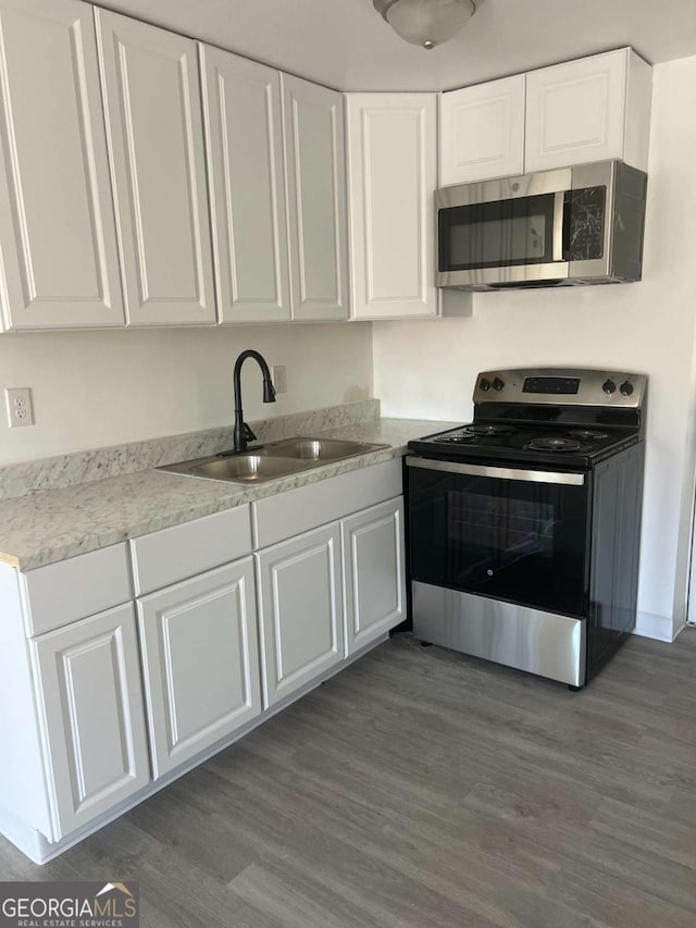 kitchen with white cabinetry, stainless steel appliances, sink, and wood-type flooring