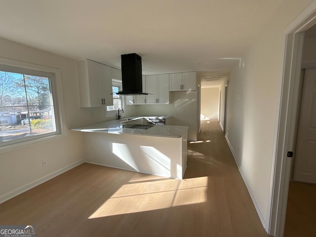 kitchen with white cabinetry, sink, ventilation hood, kitchen peninsula, and light hardwood / wood-style floors