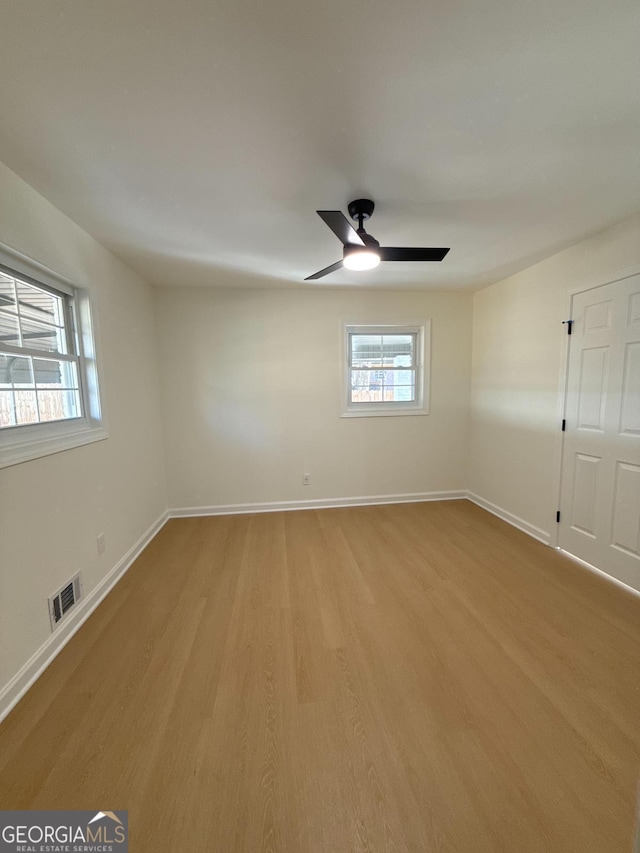 spare room featuring ceiling fan, light hardwood / wood-style flooring, and a healthy amount of sunlight