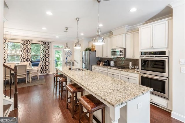 kitchen with sink, decorative light fixtures, a kitchen bar, a kitchen island with sink, and appliances with stainless steel finishes