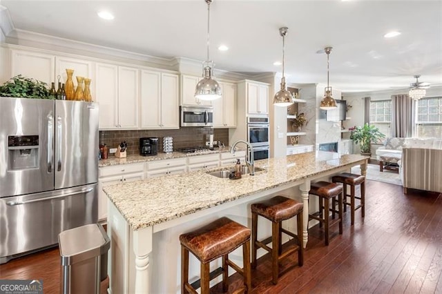 kitchen featuring pendant lighting, a breakfast bar, a kitchen island with sink, sink, and appliances with stainless steel finishes