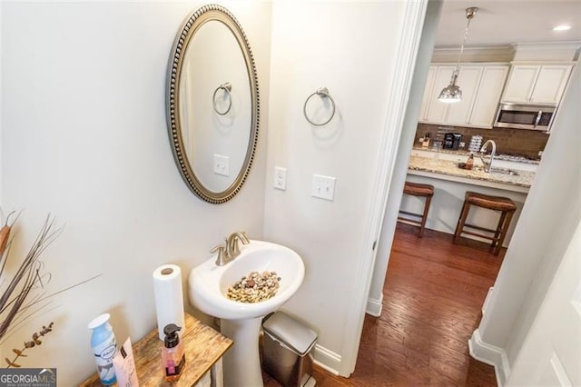 bathroom with hardwood / wood-style flooring, sink, and tasteful backsplash