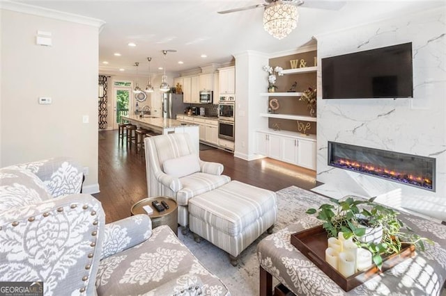 living room featuring ceiling fan, sink, dark hardwood / wood-style floors, crown molding, and a fireplace