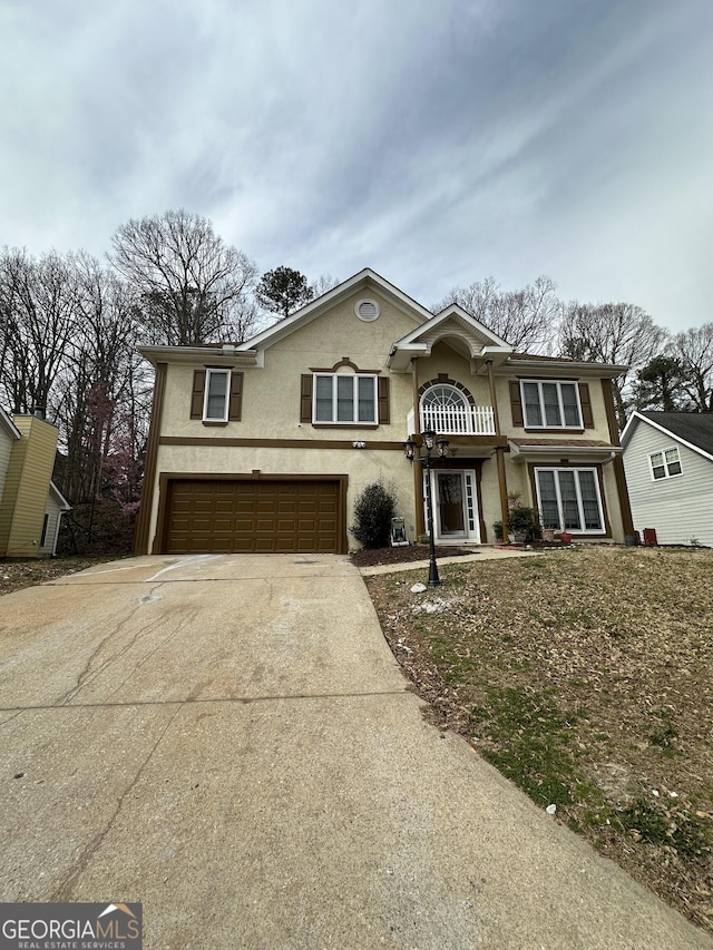 view of front of home featuring stucco siding, a garage, concrete driveway, and a balcony