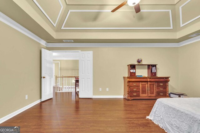 bedroom with hardwood / wood-style flooring, a raised ceiling, ceiling fan, and ornamental molding