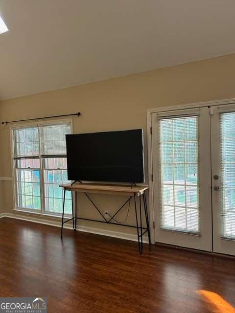 unfurnished living room featuring plenty of natural light, dark hardwood / wood-style floors, and french doors