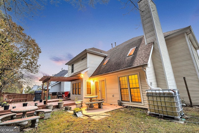 back house at dusk featuring a pergola and a patio