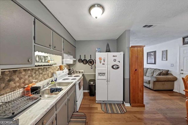 kitchen with a textured ceiling, dark hardwood / wood-style flooring, sink, and white appliances