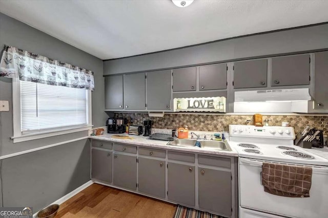 kitchen featuring electric range, decorative backsplash, gray cabinetry, and sink