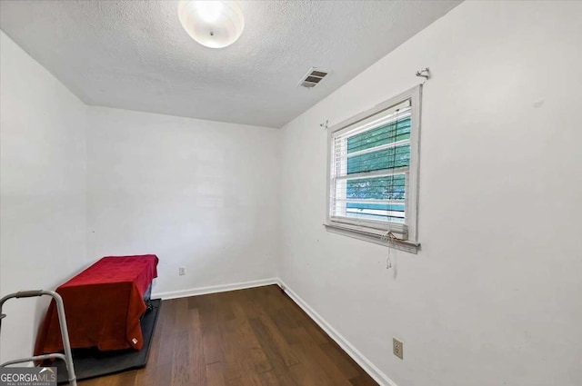 unfurnished room with dark hardwood / wood-style floors and a textured ceiling