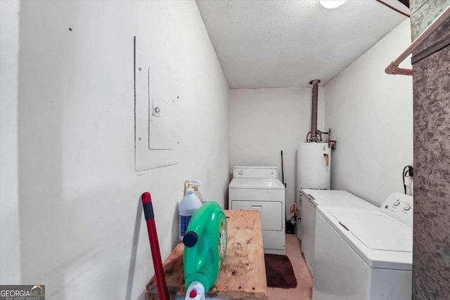 clothes washing area featuring washer and clothes dryer, gas water heater, and a textured ceiling