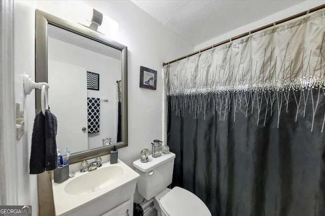 bathroom with a textured ceiling, vanity, and toilet