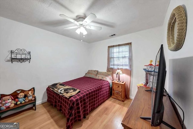 bedroom featuring ceiling fan, a textured ceiling, and light hardwood / wood-style flooring