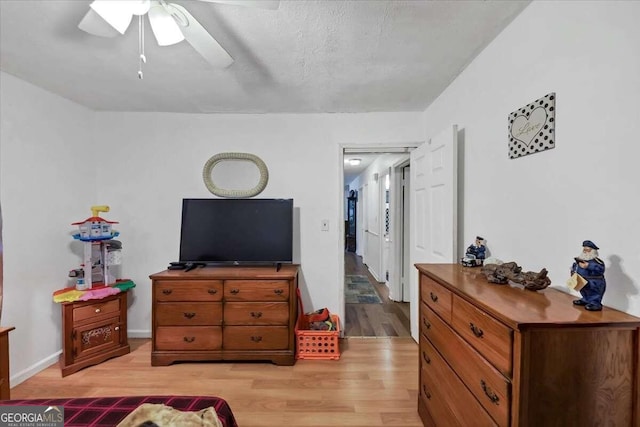 bedroom with ceiling fan, light wood-type flooring, and a textured ceiling