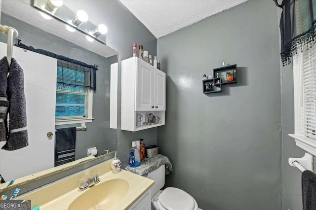 bathroom with vanity, toilet, and a textured ceiling