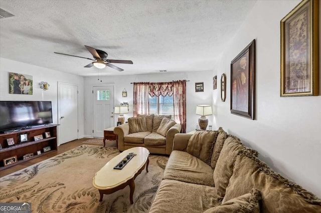 living room featuring ceiling fan and a textured ceiling