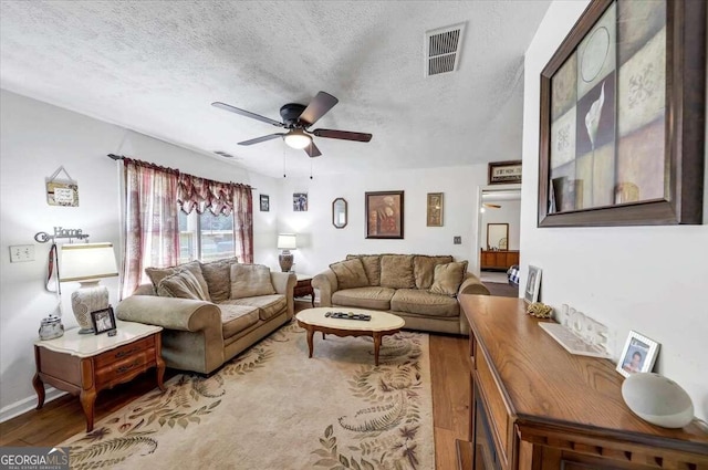 living room featuring wood-type flooring, a textured ceiling, and ceiling fan