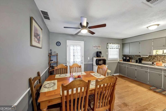 dining area with ceiling fan, a textured ceiling, a wealth of natural light, and light hardwood / wood-style flooring