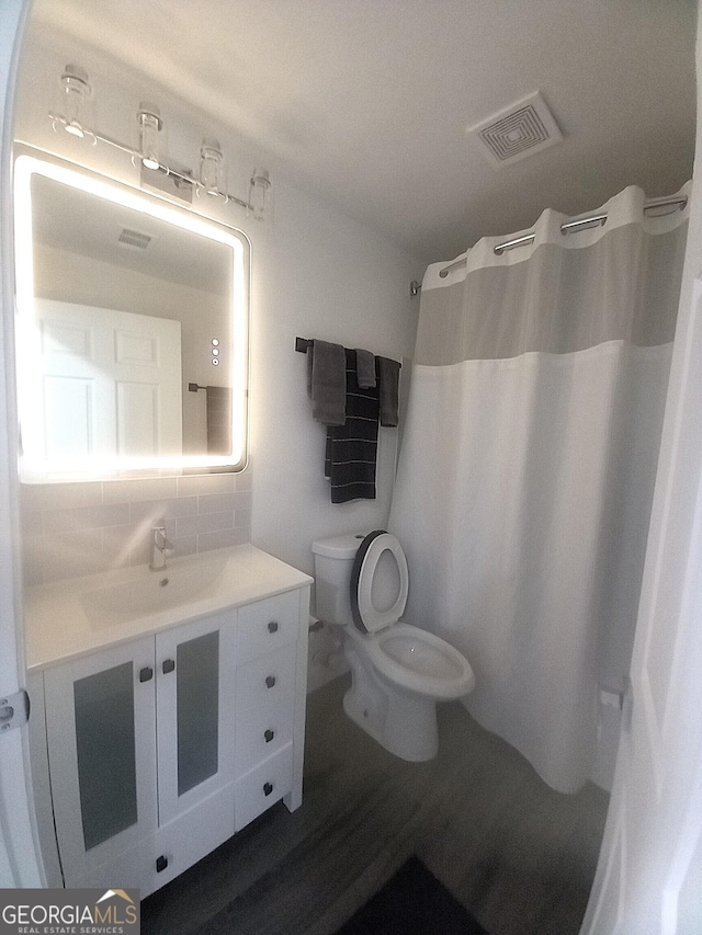 bathroom featuring tasteful backsplash, a shower with curtain, hardwood / wood-style floors, toilet, and vanity